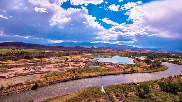 Afbeelding van rivier en vijver door woestijnvelden met bergen en zonnestralen