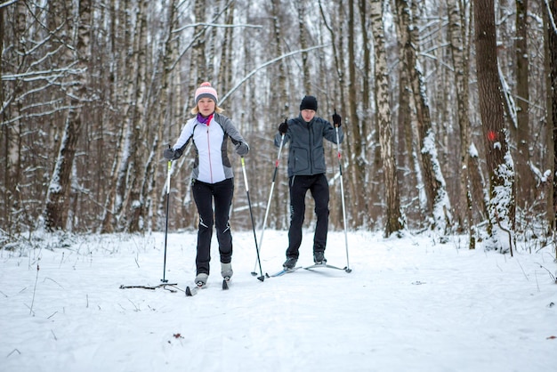 Afbeelding van sportvrouw en man skiën in winterbos