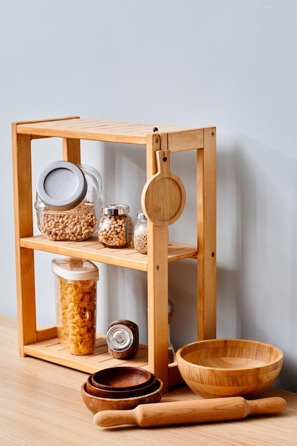 Afbeelding van verschillende granen en pasta in glazen containers die op houten planken in de keuken staan