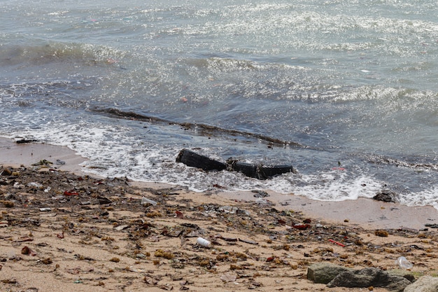 Afbeelding van vuile strand gevuld met lege plastic waterfles en plastic vervuiling, vuilnis en afval op vuile zandstrand en niemand