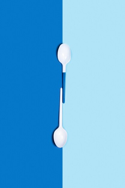 Foto afbeelding van witte plastic lepels op een tweekleurige blauwe achtergrond