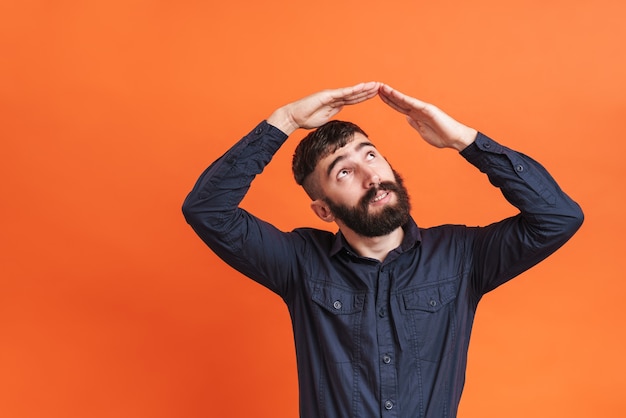 Afbeeldingsclose-up van een brunette man die twee handen boven zijn hoofd houdt en een dakgebaar maakt