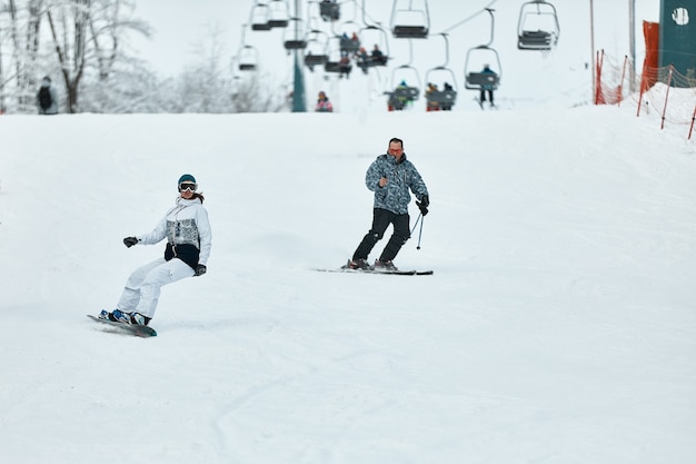 Afdaling skiër. Snowboarders en skiër rijden op sneeuw in de bergen. Bergaf rijden. Avontuurlijke skiërs seizoen. Ski- en snowboardresorts. Ski- en snowboarduitrusting. Liefhebbers van sneeuwsporten.