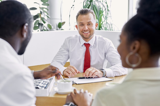 Photo affable caucasian professional salesman show the document to customers