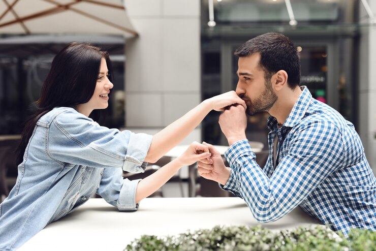 Photo affectionate boy kisses girl hand in outdoor cafe.