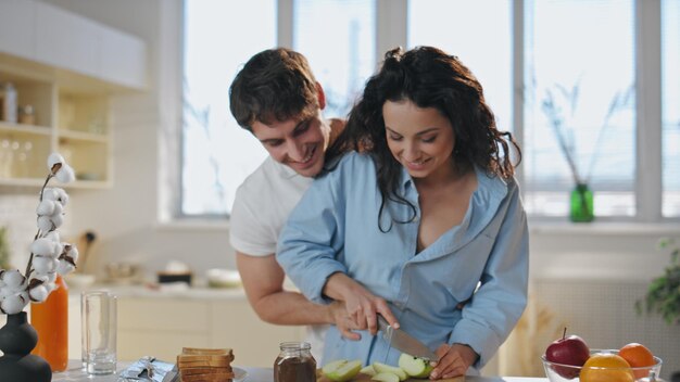 Foto una coppia affettuosa che cucina, che si abbraccia, che ride insieme al primo piano mattutino.