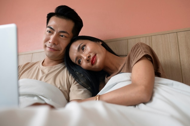 Affectionate couple using laptop together in bed