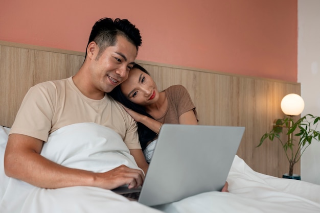 Affectionate couple using laptop together in bed