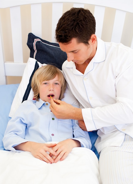 Photo affectionate father checking his son's temperature