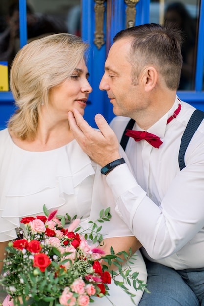 Affectionate mature couple in love embrace close to one another. Man touches woman's chin