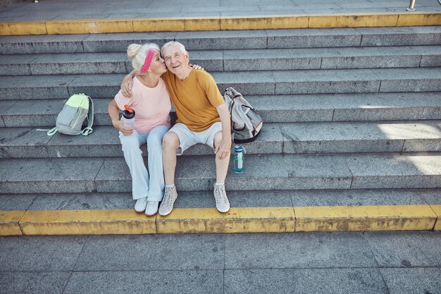 Affectionate senior female pensioner with a bottle of water kissing her husband on the cheek