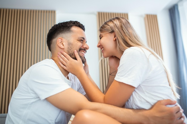 Affectionate young attractive couple sharing a romantic moment in the bedroom at home Happy young couple hugging and smiling while lying on the bed in a bedroom at home