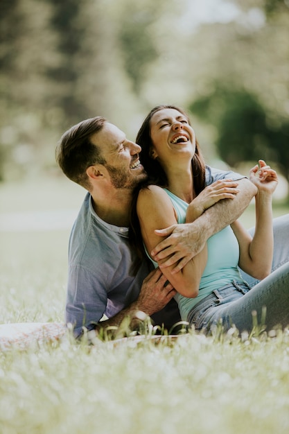 Photo affectionate young couple sitting on the green grass at the park