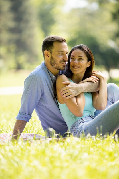 affectionate young couple sitting on the green grass at the park