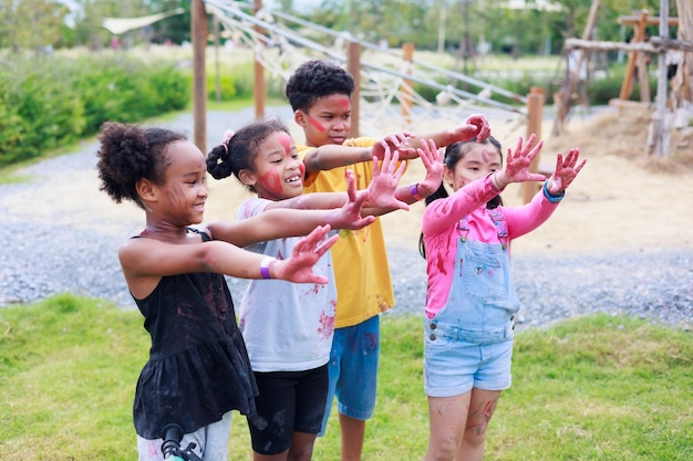 アフリカの子供とアジアの女の子がカラフルな手を示す 夏のキャンプ学習で遊び場で遊ぶ多様な幸福の子供グループ