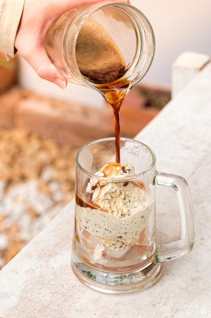 Affogato koffie met ijs op een glazen beker met witte houten tafel.