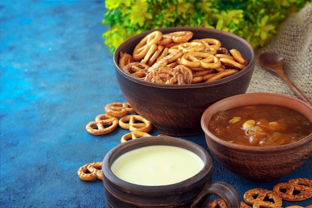 Afgebrokkelde pretzels op een weefselachtergrond met melk in een kleikop