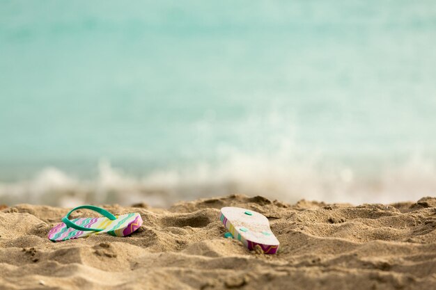 Afgedankte slippers op zandstrand bij oceaan