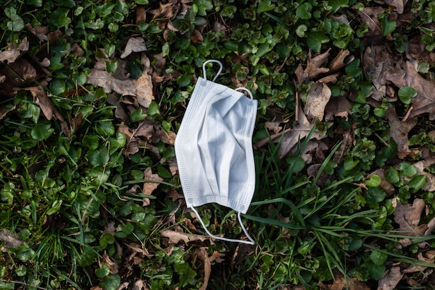 Afgedankte wegwerp medische gezichtsmasker ter bescherming tegen infectie op gras