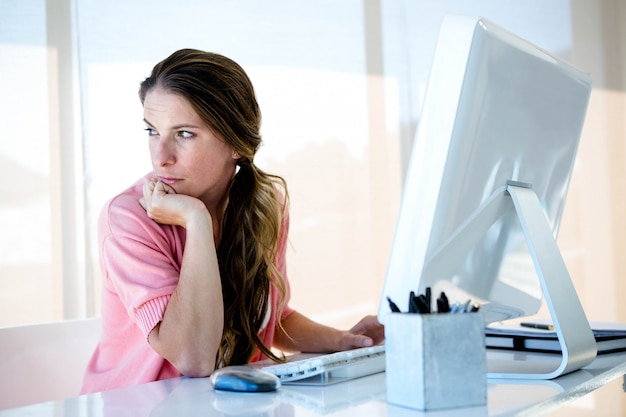 afgeleid zakelijke vrouw zit aan haar bureau, wegkijken van haar computer