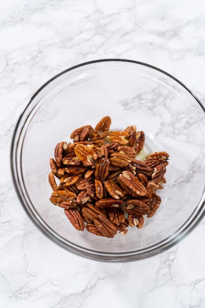 Afgemeten ingrediënten in een glazen mengkom om geroosterde pecannoten te maken