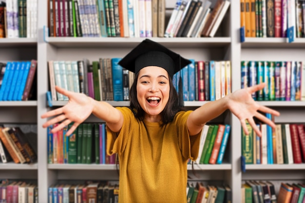 Afgestudeerd meisje voor een bibliotheek