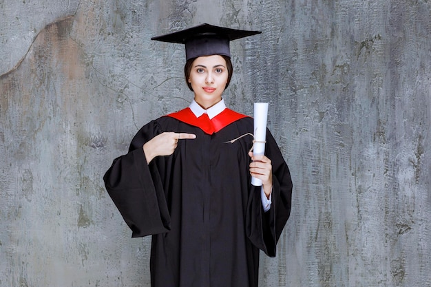 Afgestudeerde jonge vrouw in toga met universitair diploma. hoge kwaliteit foto