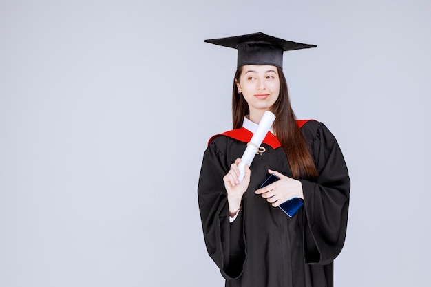 Afgestudeerde student in toga mobiele telefoon in de hand met diploma. Hoge kwaliteit foto