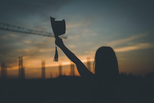 Afgestudeerden dragen een zwarte hoed om te staan voor felicitaties met afstuderen op silhouet zonsondergang tijd