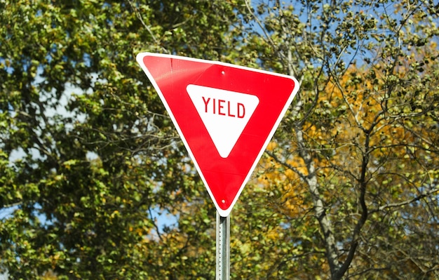 afgiftebord op de weg dat voorzichtigheid symboliseert en plaats maakt voor tegemoetkomend verkeer tegen een heldere blauwe hemel