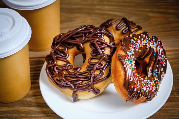 Afhaalmaaltijden koffie en chocolade donuts op houten tafel.