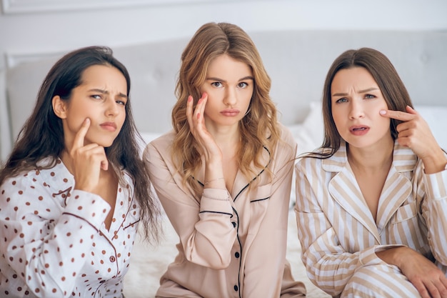 Afraid of aging. Three girls touching their skin looking unsatisfied