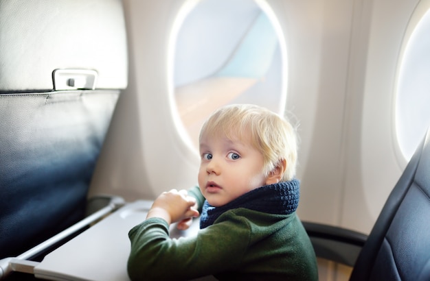 飛行中に航空機の窓のそばに座って怖い男の子