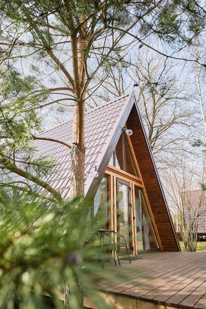 Aframe wooden cabin with a blurred pine tree on foreground