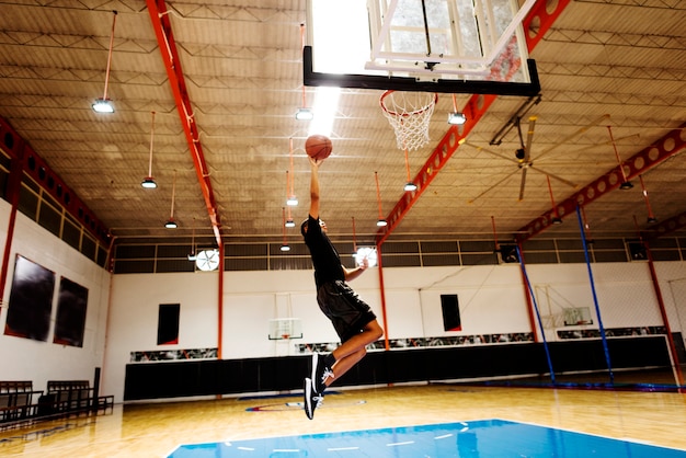 Африканский американский подросток играет в баскетбол один на корте