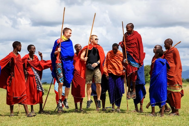 사진 아프리카 탄자니아 마사이 마을 2016년 3월 4일 유럽 관광객과 지역 주민들이 마사이 부족의 국가 춤을 추고 있습니다.