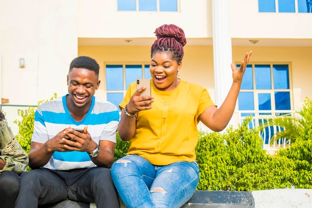 african adult laughing and joking while looking at their phone