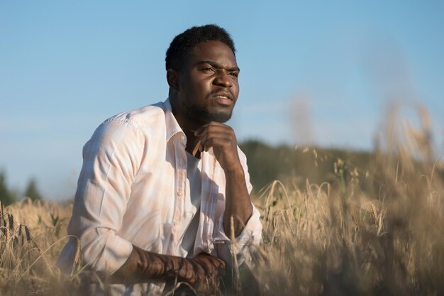 African american agriculturist sits on wheat field smiling