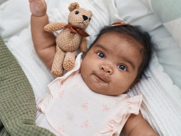 African american baby lying on bed covering with blanket at bedroom