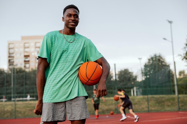 African american basketball player standing at basketball court smiling looking at camera 