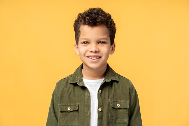 African American boy in casual clothes posing in studio isolated on yellow background