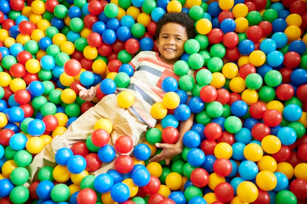 Photo african-american boy playing in ballpit