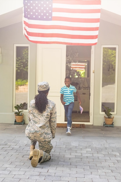 African american boy running towards soldier mother arriving at home