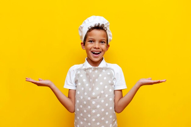 African american boy in uniform and chef's hat holds empty hands and chooses