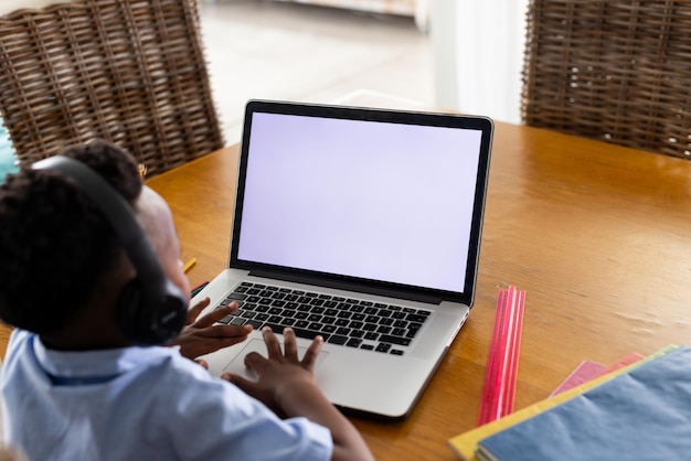 Африканский американец в наушниках и использует ноутбук с копировальным пространством на экране для онлайн-урока