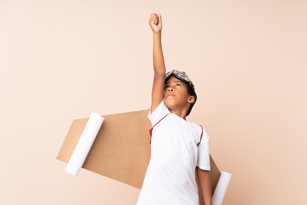 African American boy  with aviator hat and with wings over isolated wall