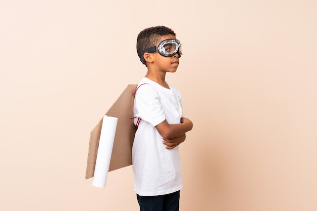 African american boy with aviator hat and with wings with his\
arms crossed