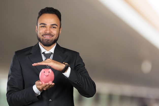 African American business man holding a piggy bank