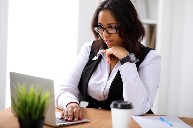 African american business woman is busy with laptop in office while sun shines outdoors