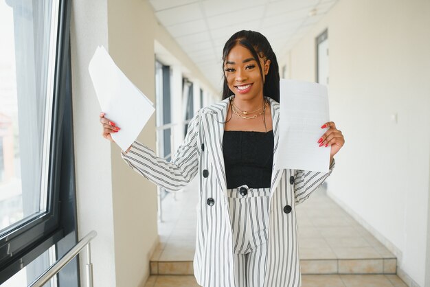 African american business woman standing, office hall with documents